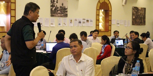 Participants listen to Dr. Navarro's point. Photo shows their articles and other workshop outputs posted on the wall for everyone's scrutiny.